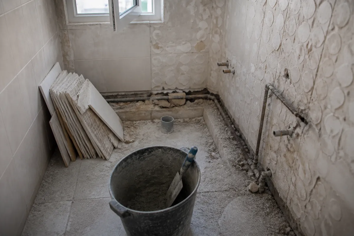 Reforma de baño en curso en Murcia, con tuberías vistas y material de obra