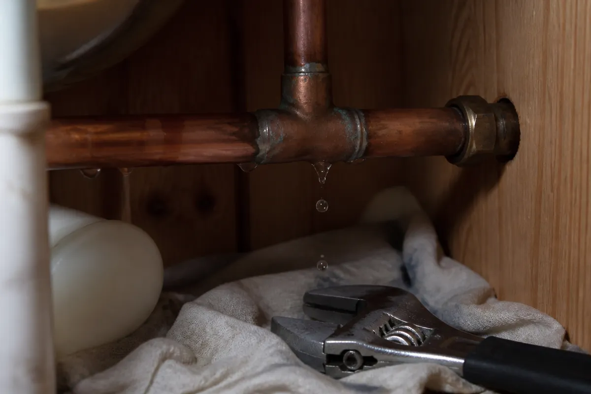 Reparación de una fuga de agua en una junta de cobre bajo un mueble de baño en Murcia